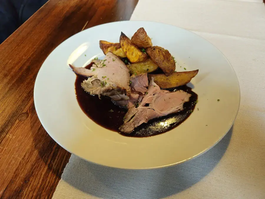 Tranches de rôti de porc servies avec des pommes de terre rôties et un jus brun