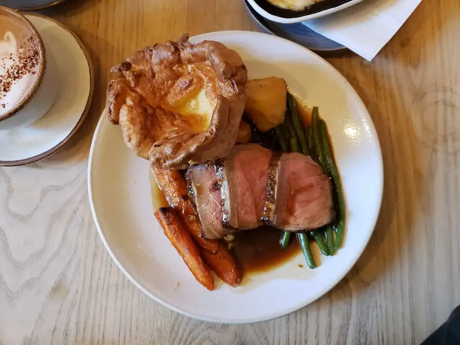 Rôti de bœuf cuit servi en tranches avec légumes verts et jus