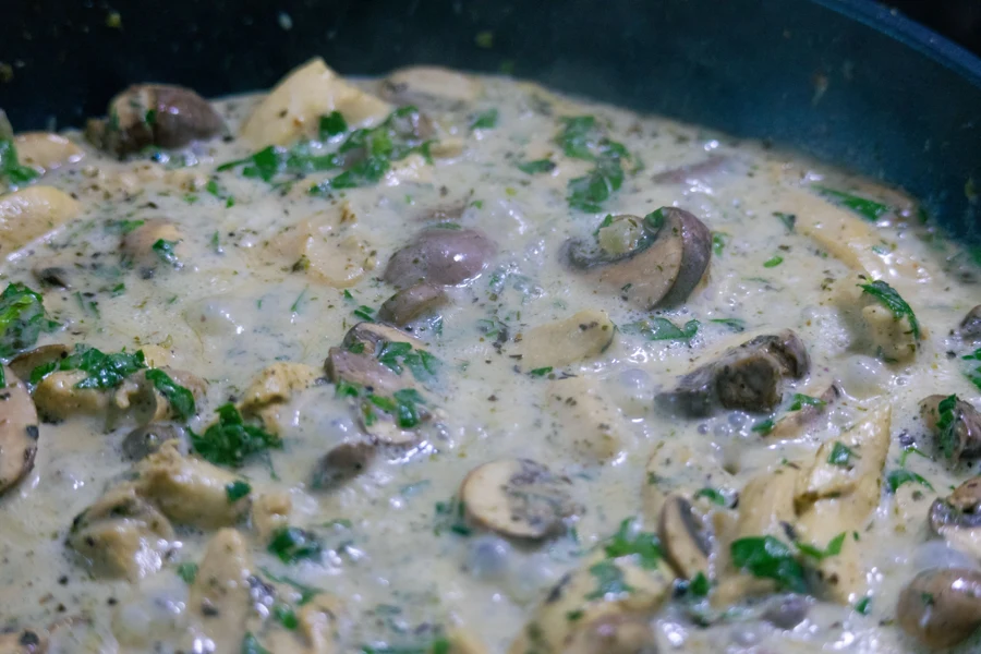 Champignons en tranches nappés de sauce à la crème et de persil dans une poêle