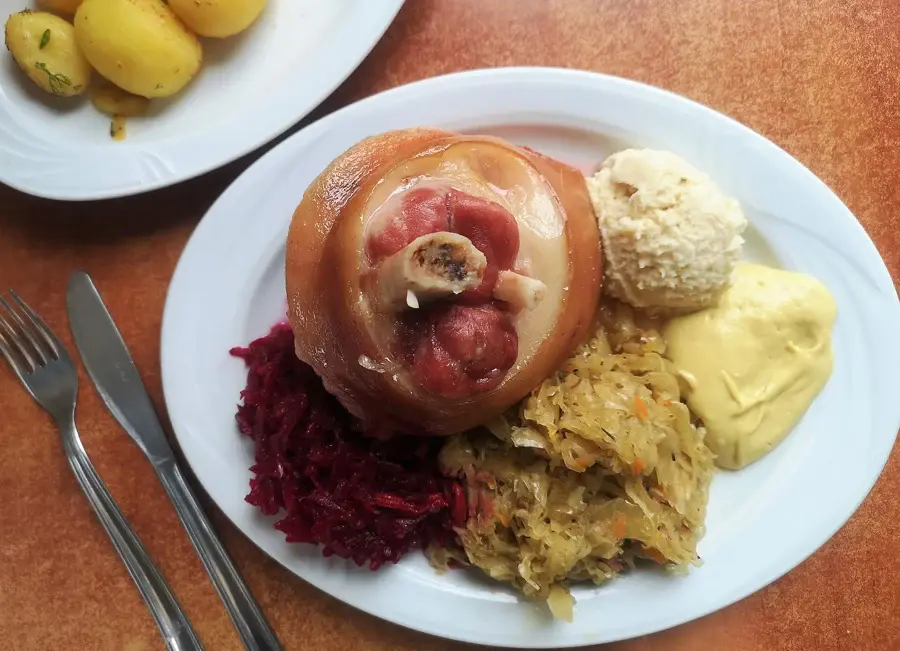 Jarret de porc cuit servi avec choucroute, purée et moutarde dans une assiette
